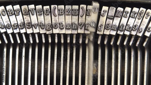 Old vintage mechanical typewriter typebars hammers striking the letters, close-up macro detail