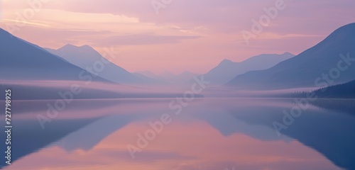 Stunning sunset over a calm lake reflecting vibrant hues of pink and orange mountains.