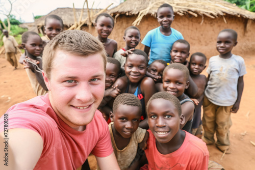 Male volunteer poses with children for selfies in an African village. Charitable assistance to children in need