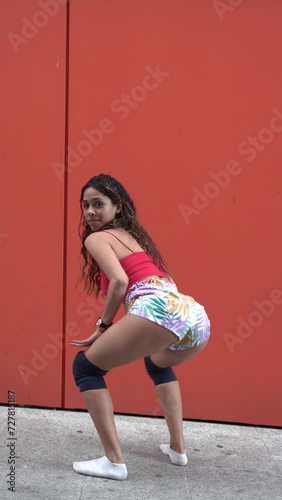 Amazing young woman shaking ass in side view twerking dance. 4K Video Footage of attractive woman in tight shorts performing seductive dances and twerk isolated on red background.