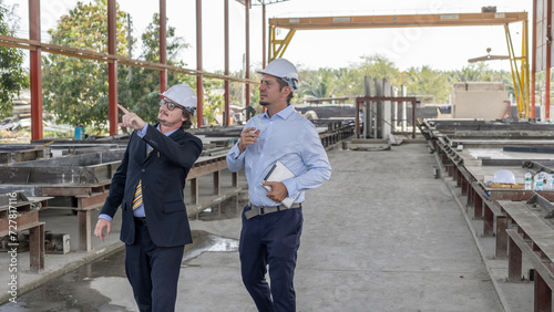 Two managers or civil engineers work together to inspect production of prefabs factory. Factory owner and manager are checking the production systems