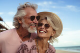 pareja de hombre y mujer seniors sonrientes, vistiendo  ropa de verano y gafas de sol, posando sobre fondo de paisaje de playa y mar,  con cielo azul al atardecer