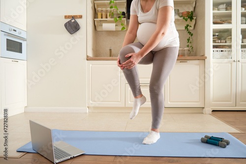 Yoga at home during pregnancy and problems with getting a knee injury. Pregnant woman on Vorkuta holds on to a sprain on her leg, exercises to prepare for childbirth photo