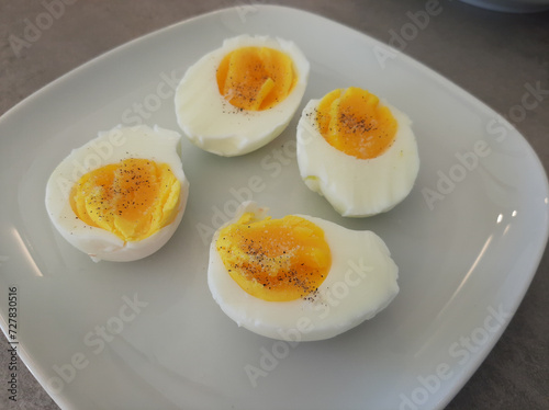 Two boiled sliced eggs arranged on a white plate