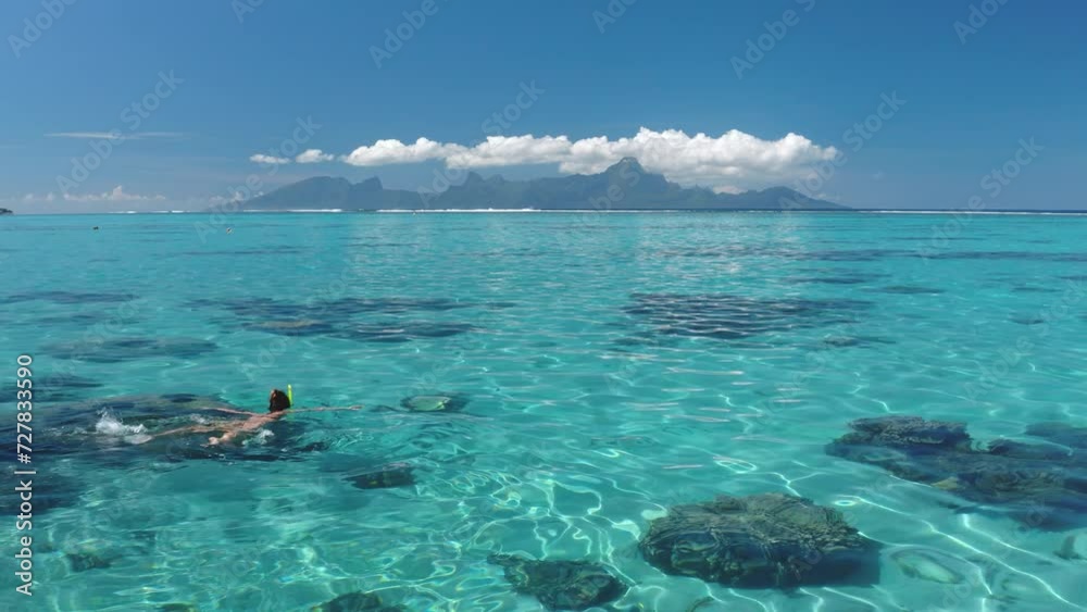 Woman snorkel crystal blue sea water. Person explore coral reef underwater wild life in sunny day. Outdoor lifestyle travel on summer holiday vacation. Tahiti exotic paradise island, French Polynesia