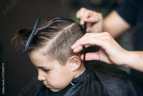 Little boy on a haircut in the barber sits on a chair