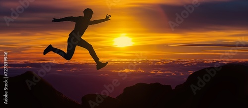 Man jumping over rocks in the mountains at sunset. Freedom, risk, challenge, success.