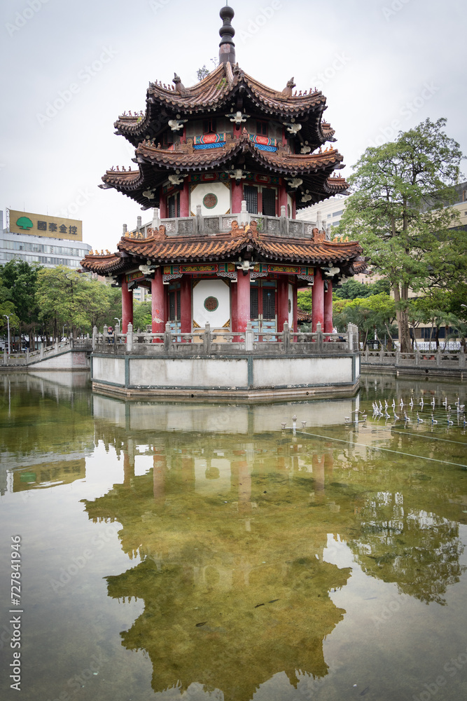 Small Asian temple in city park reflected in a pond, vertical shot, Taipei, Taiwan