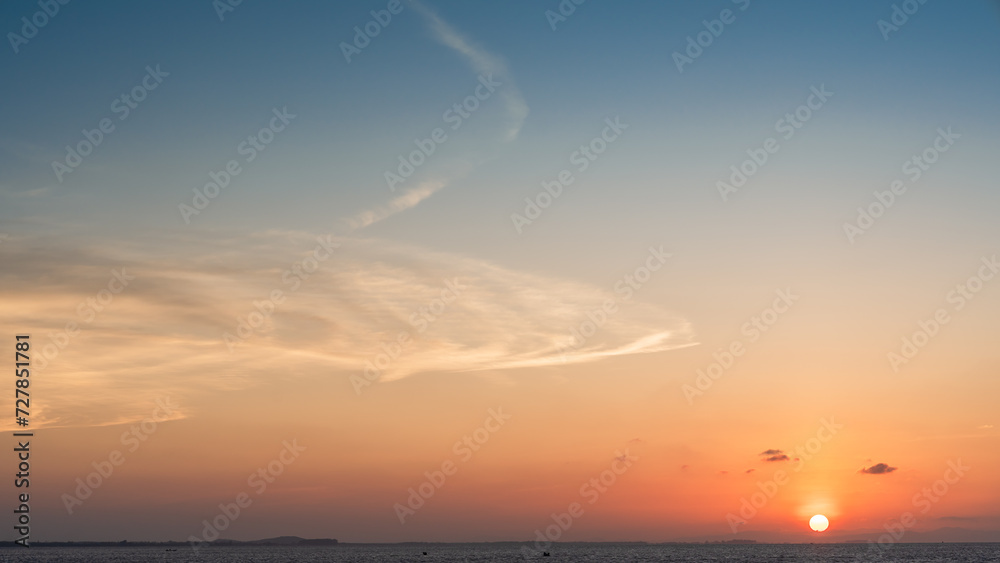 Sunset sky clouds over sea in the evening with sundown and orange sunlight in golden hour, Horizon sea landscape background 