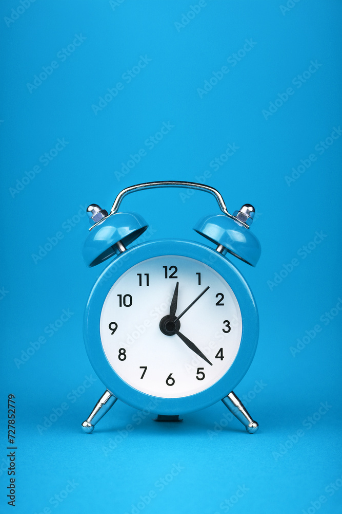 Close up one blue alarm clock over blue background Close up one blue alarm clock over blue background