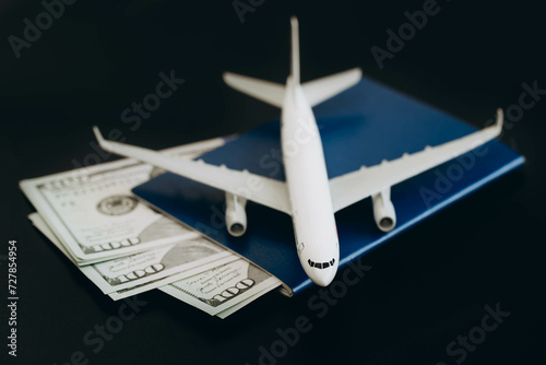 Airplane toy with passports and money on black background. Air trip and vacation.