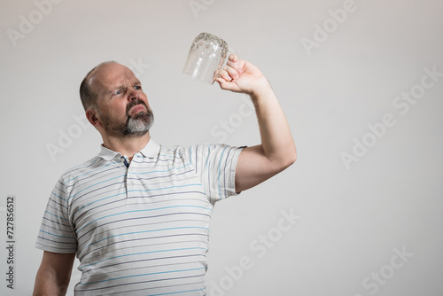 Caucasian man staring at empty beer glass, white background. Conceptual image of The Dry Challenge