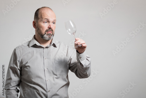 Caucasian man staring at empty wine glass, white background. Conceptual image of The Dry Challenge