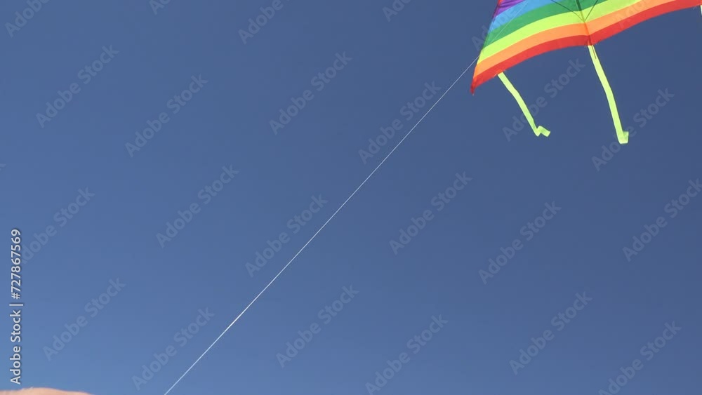 Multicolor kite flies up in the clear blue sky