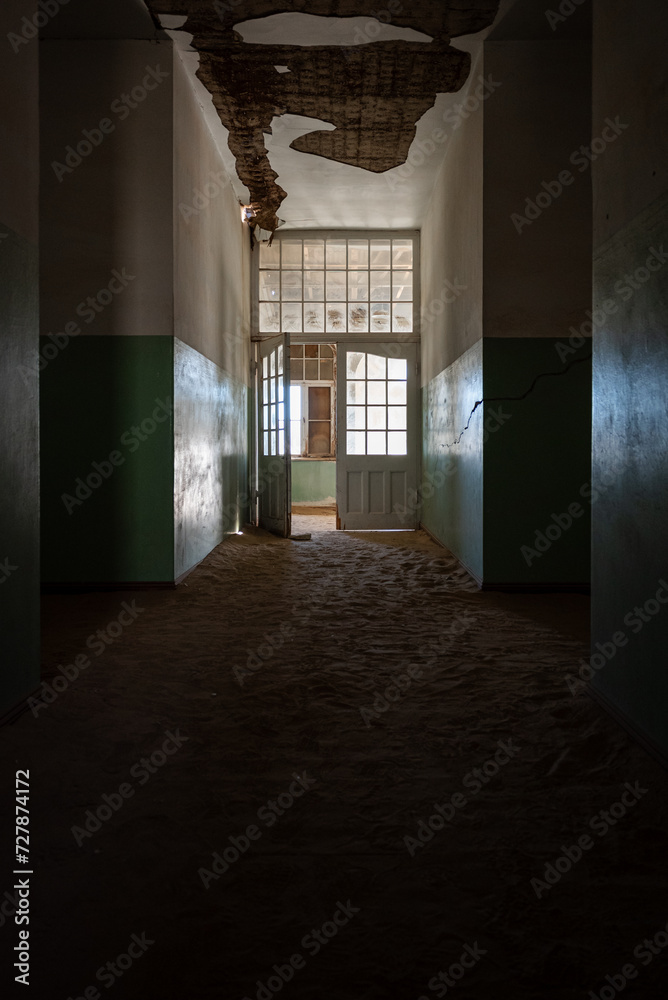 Abandoned, dilapidated building with dimly lit interiors showcasing aged brown flooring and walls