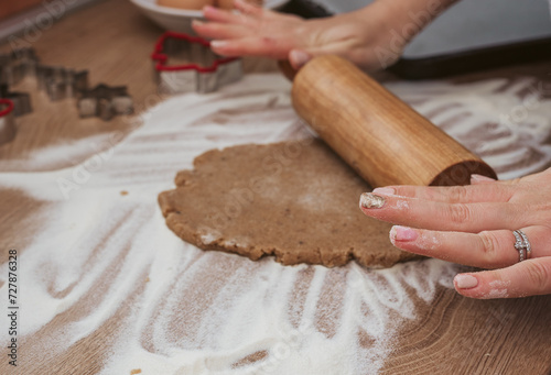 Close-up photo of hands using rolling pin on cookie dough for christmas cookies