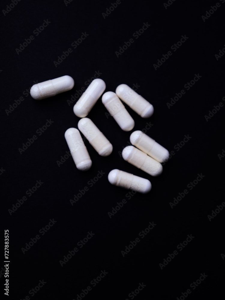 Creatine capsules on dark paper background. Soft focus. Close up. Copy space Creatine capsules on dark paper background. Soft focus. Close up. Copy space