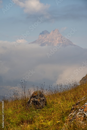 Russia. The Elbrus region. The high mountain peaks of the North Caucasus are surrounded by morning misty clouds hovering at different levels of inaccessible rocks.