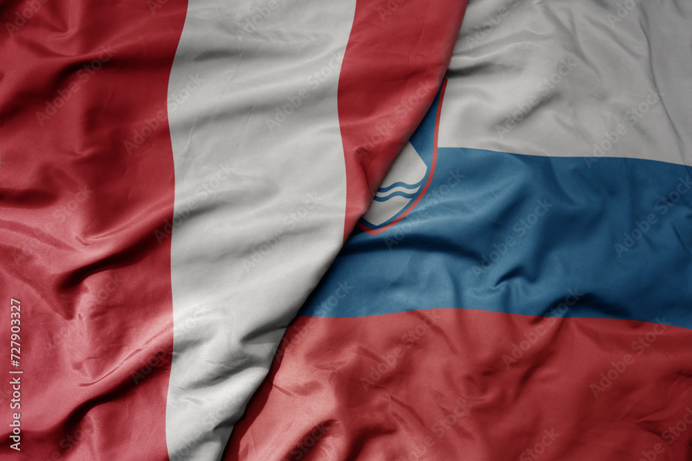 big waving national colorful flag of slovenia and national flag of peru .