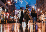 Young adults strolling through a city street at night with festive lights.