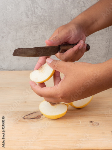 pears are peeled using a hand knife, on a wooden table placed on a white plate