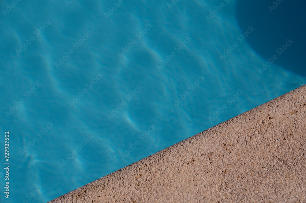 Blick auf einen Pool bei Sonne mit Randstein als Designelement oder Hintergrund mit blank space