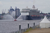 Inaugural call of modern cruiseship cruise ship liner into port of Hamburg, HH in Germany with fireboat saluting with water fountain