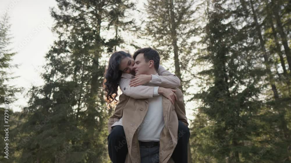 Couple at each other against background century-old trees creates picture moment happiness in nature. A girl on her boyfriend's shoulders. Relaxing and flirting young couple in love in nature. Couple at each other against background century-old trees creates picture moment happiness in nature. A girl on her boyfriend's shoulders. Relaxing and flirting young couple in love in nature.