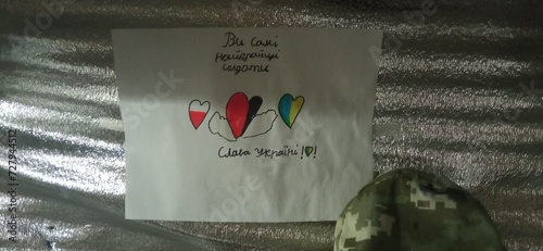 Childish letter to ukrainian warriors near military hat on silver background