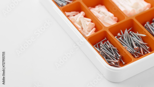 Closeup of orange tool case with srews and wall plugs. (ID: 727955755)