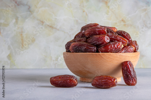 Date fruits in wooden bowl,in front of bright background photo