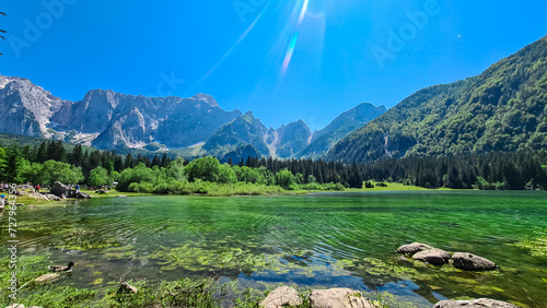 Panoramic view of Superior Fusine alpine Lake (Laghi di Fusine) with majestic Mount Mangart in background in Tarvisio, Friuli Venezia Giulia, Italy. Captivating Water Reflection in tranquil atmosphere photo