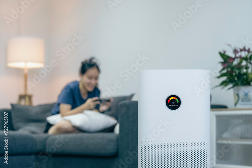 Air purifier, PM 2.5 dust filter, clean and health air. Air purifier against blurred woman using the phone on sofa in living room. . photo
