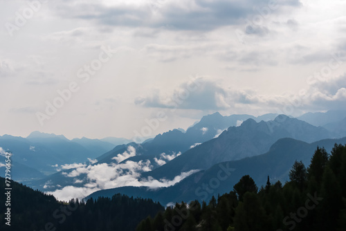 Panoramic view from Monte Lussari in Camporosso, Friuli Venezia Giulia, Italy. Looking at majestic mountain peaks of Julian Alps and Karawanks, border to Austria Slovenia. Misty atmosphere in nature