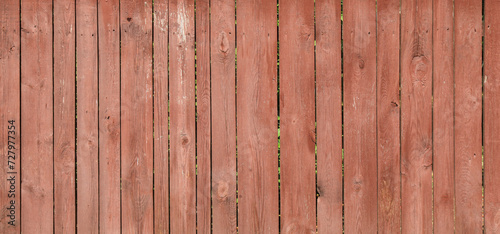 Red wooden surface, backdrop, background. Front view of an old wooden fence for inscription. Pink wood fencing. Surface, faded in the sun, shabby fence. Wooden fence boards with very faded pale paint