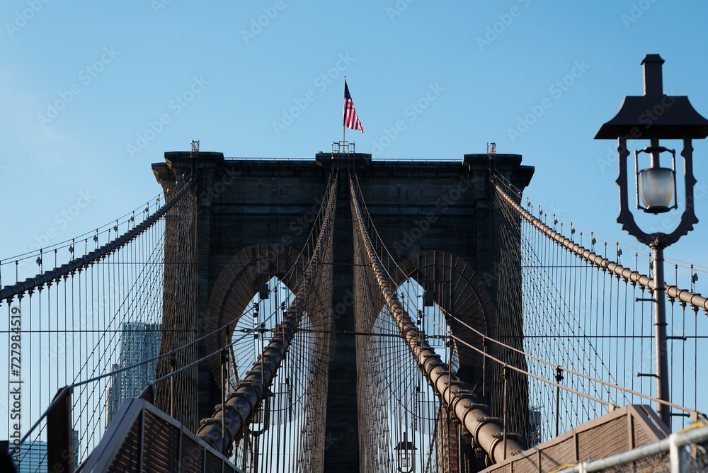 Obraz premium Drapeau américain sur un pilier du Brooklyn bridge reliant Brooklyn à Manhattan