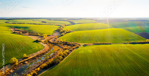 Bird s eye view of agriculture area and green wavy fields in sunny day.