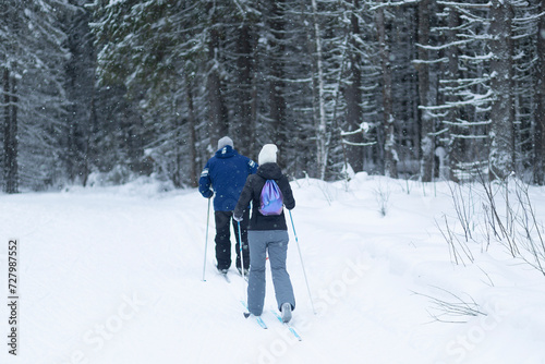 People ski in winter on a ski track through a winter forest.Cross Country skiing.