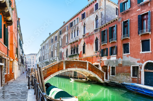 Traditional canal with boats and colorful facades of old houses in Venice, Italy.