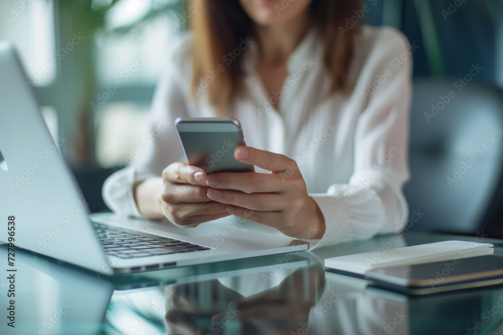 A woman sitting at a desk using a cell phone A woman sitting at a desk using a cell phone