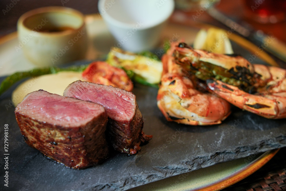 A mouthwatering dish of grilled steak and shrimp on a hot stone, offering a perfect blend of flavors for a delicious meal