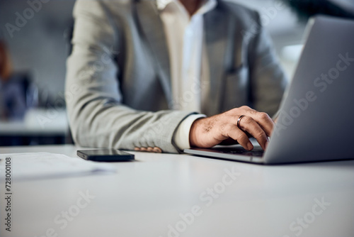 Close-up of a businessman's hands, using a laptop, dressed in a suit. photo