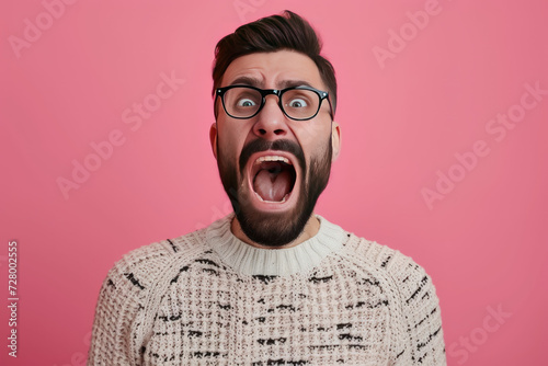 Goofy young man, with full beard and moustache screams. Studio portrait.