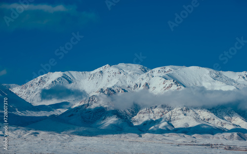 Snow covered mountain peaks with clouds in winter © chaossart