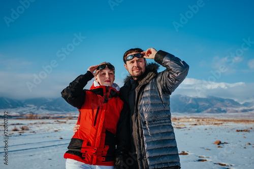 Portrait of young happy couple of tourists on mountains background in winter