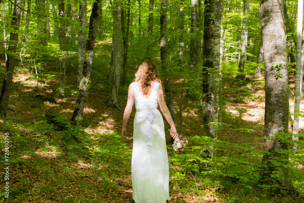 Bride in white dress walking through the spring forest in La Fageda d en Jorda, La Garrotxa, Spain Bride in white dress walking through the spring forest in La Fageda d en Jorda, La Garrotxa, Spain