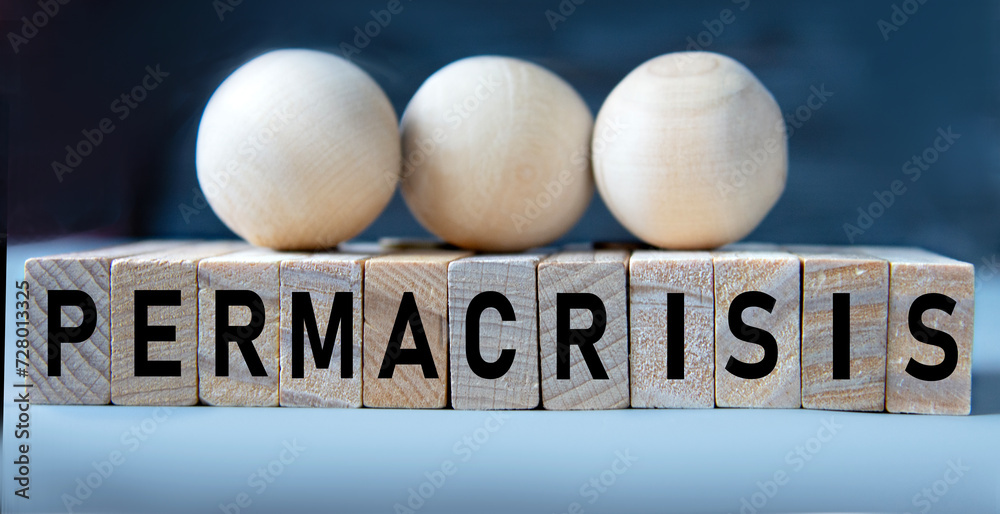 PERMACRISIS - word on wooden cubes on a blue background with wooden round balls PERMACRISIS - word on wooden cubes on a blue background with wooden round balls