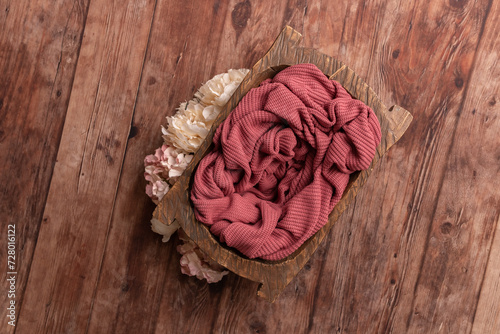 Bowl for a photo shoot of a newborn baby. Bowl with crimson background.Badeck on a wooden floor.