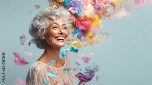 Senior Woman with Silver Hair Laughing Among a Cascade of Colorful Feathers