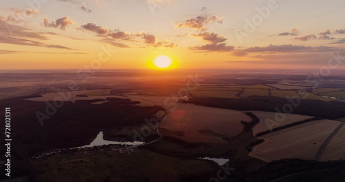Aerial countryside view. Sunset landscape. Green field in red orange color sun light evening nature scenery skyline background drone shot.